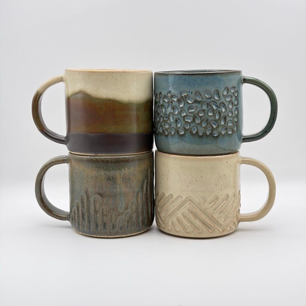 Homepage hero image Four handmade ceramic mugs in blue rutile and birch glazes, made in the Isle of Man by JFC Ceramics